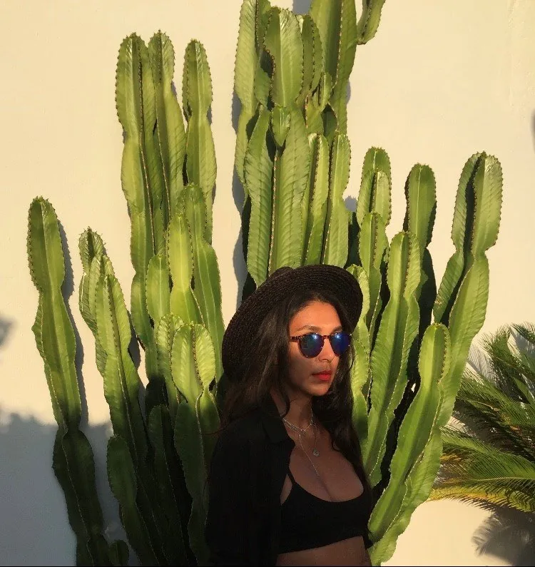 Lily Rivers in sunglasses beside a tall cactus